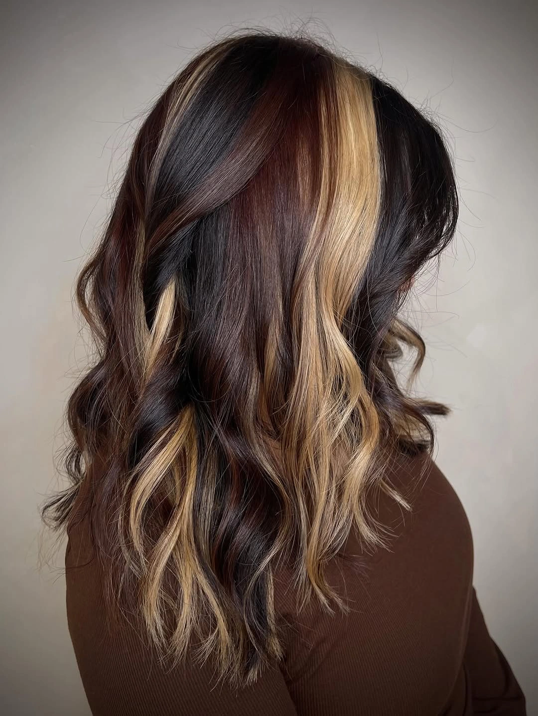 Dark wavy hair with bold blonde face framing panels