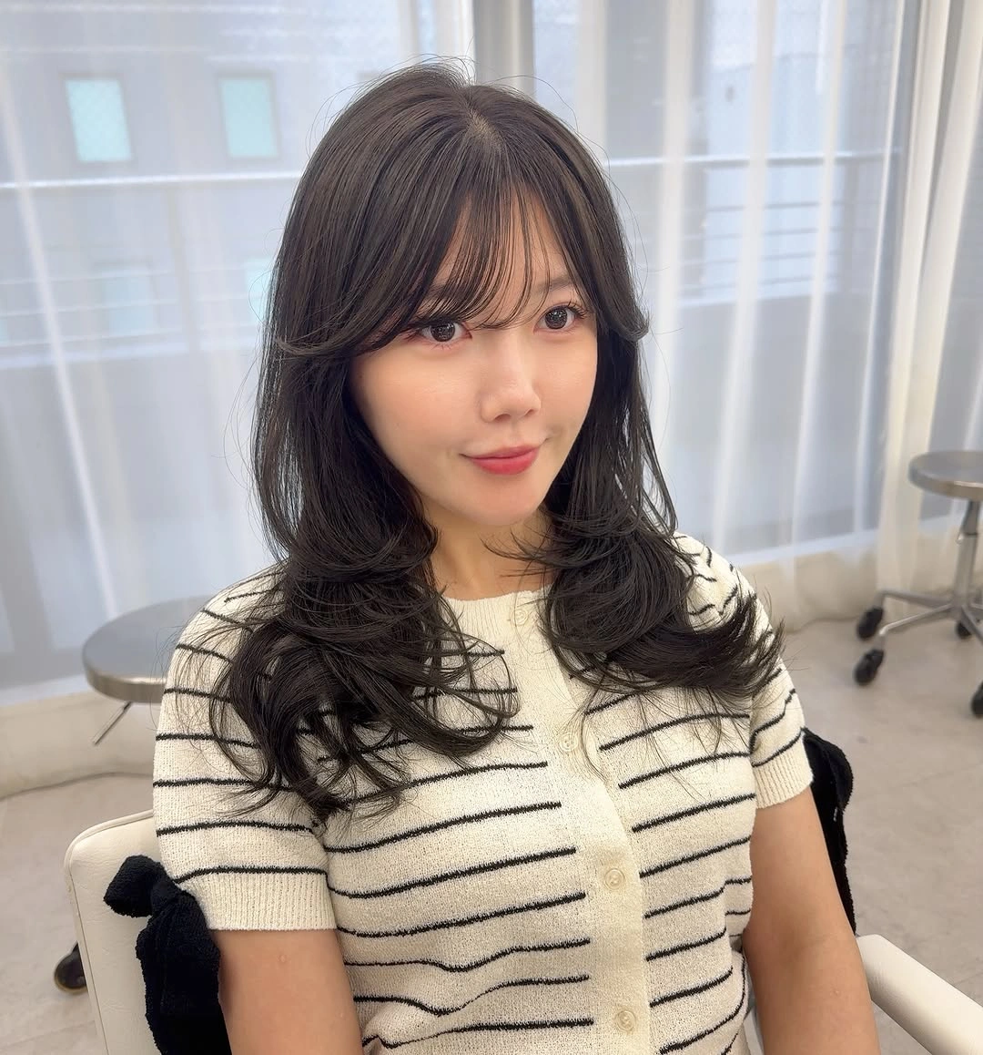 Medium brunette hair with curtain bangs and soft waves