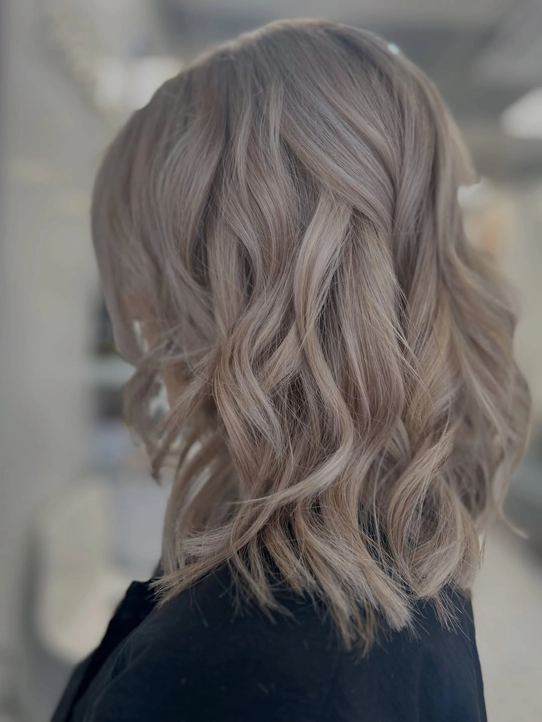 Medium ash blonde hair with repeated loose waves from the back