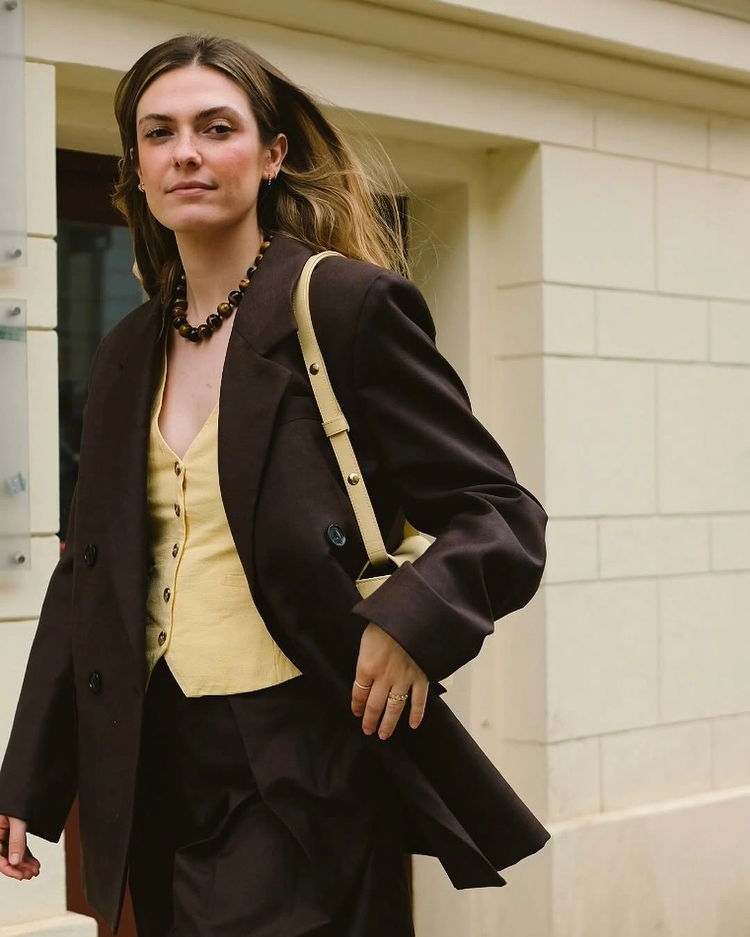 Dark brown blazer with pale yellow top and chunky necklace