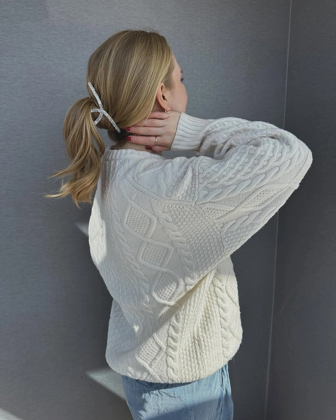White cable-knit sweater with pale jeans in a relaxed outfit