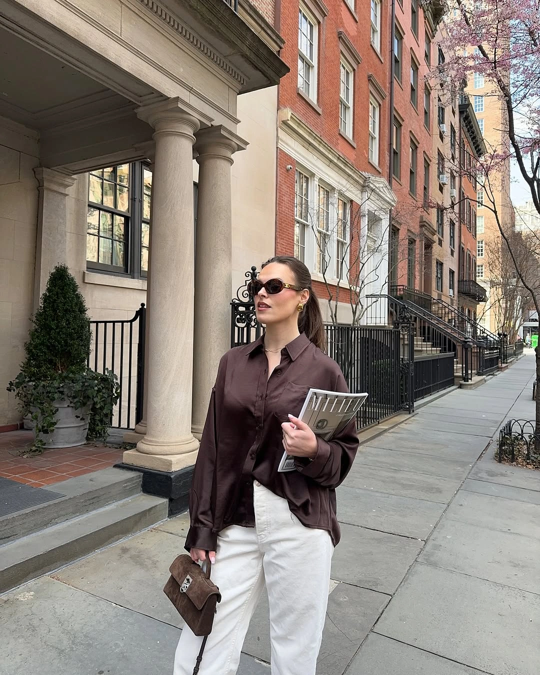 Brown jacket with white top, cream wide trousers and brown bag