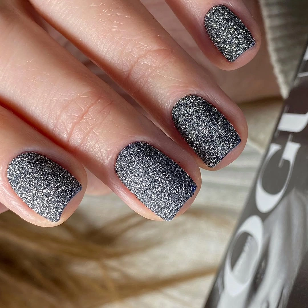 Short square charcoal nails with a dense textured sparkle finish