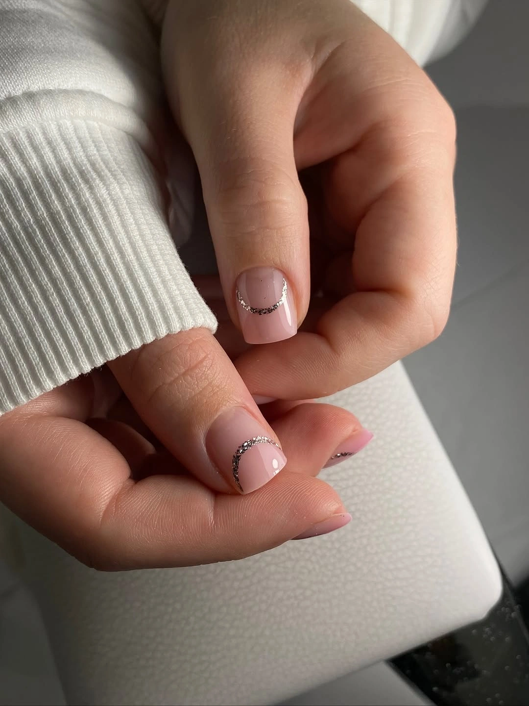Very short square pale pink nails with a thin French line