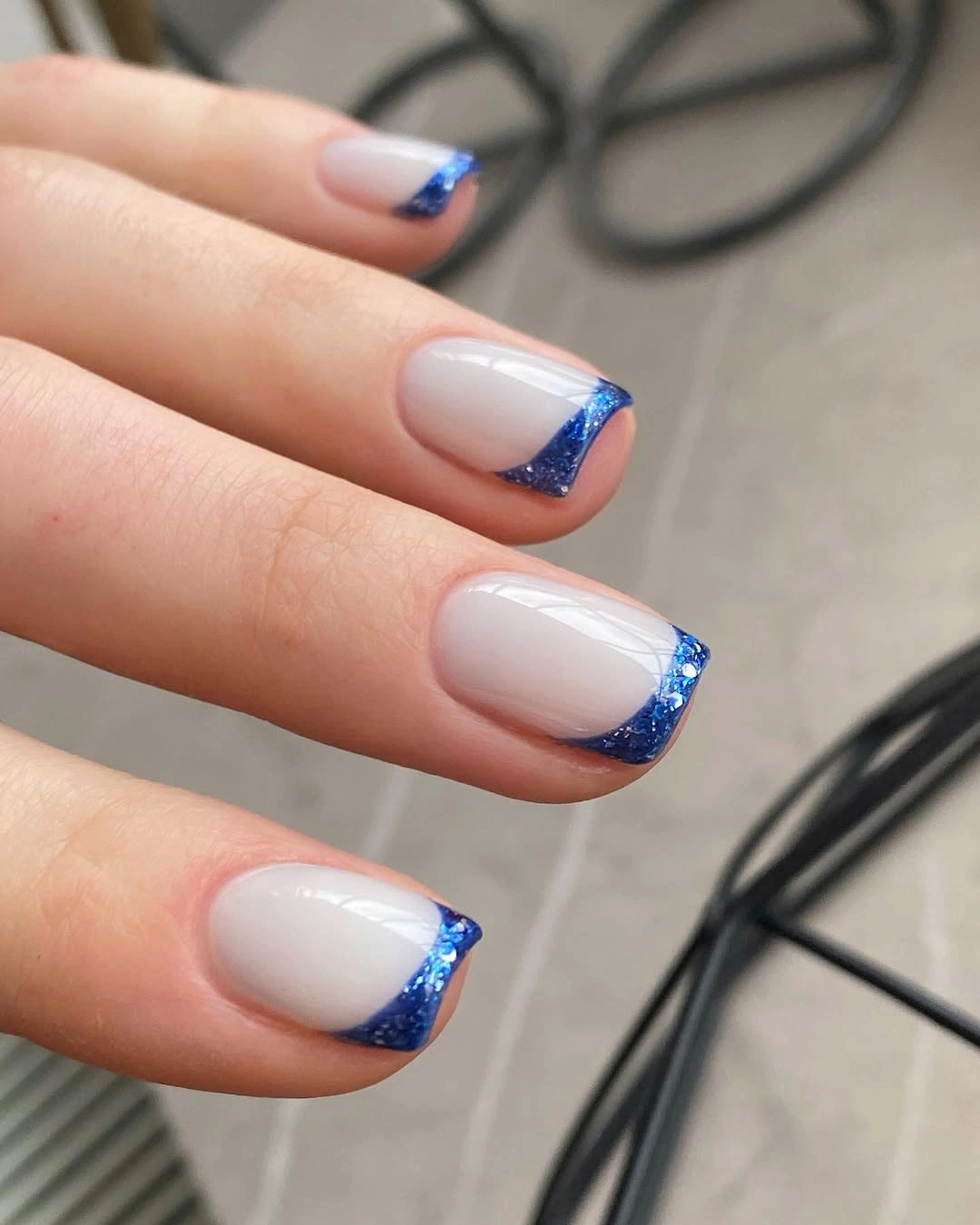 Short squoval milky nails with cobalt blue French tips