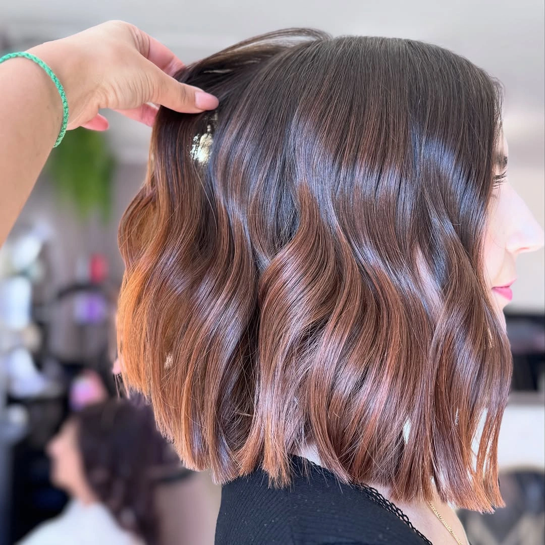 Wavy brunette bob with warm copper ribbons and lifted section