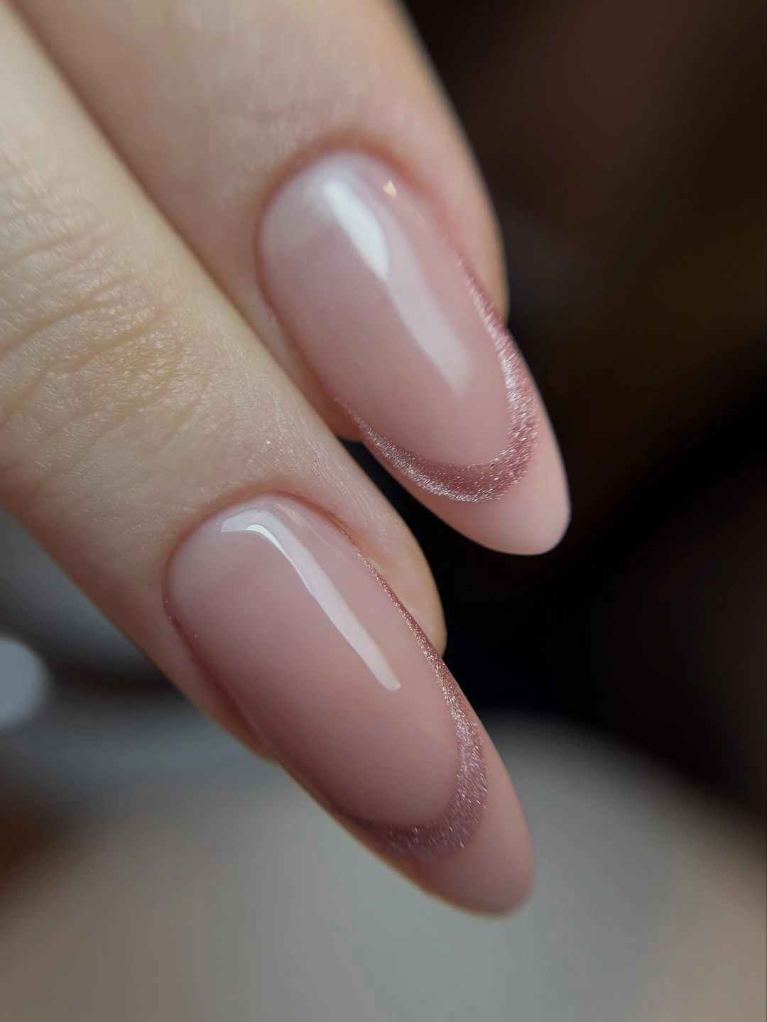 Close-up almond nails with milky pink base and rosy shimmered edges