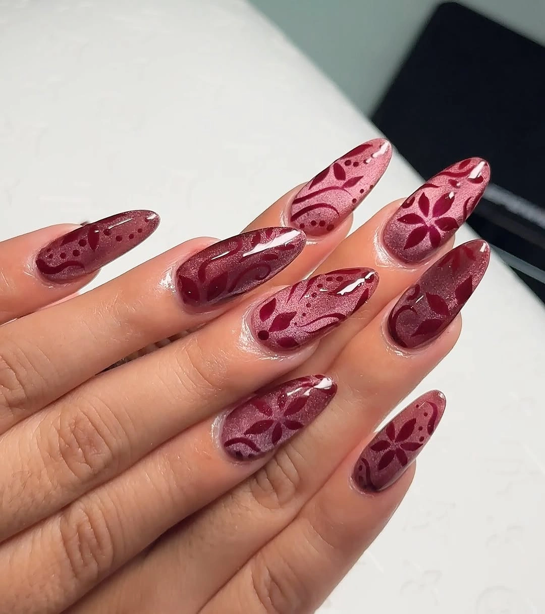 Long almond nails with tonal burgundy floral and vine-like pattern