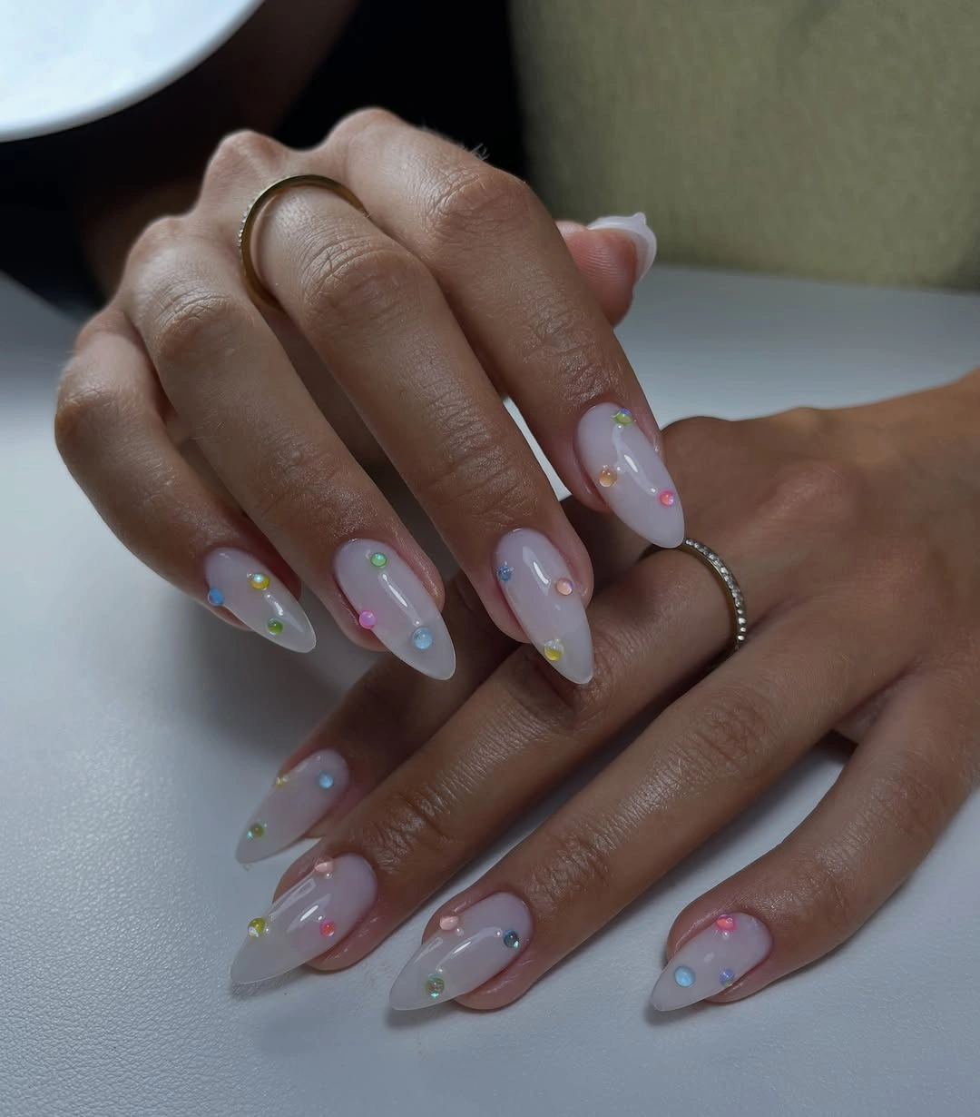 Medium-long almond nails with sheer base and scattered pastel dot accents
