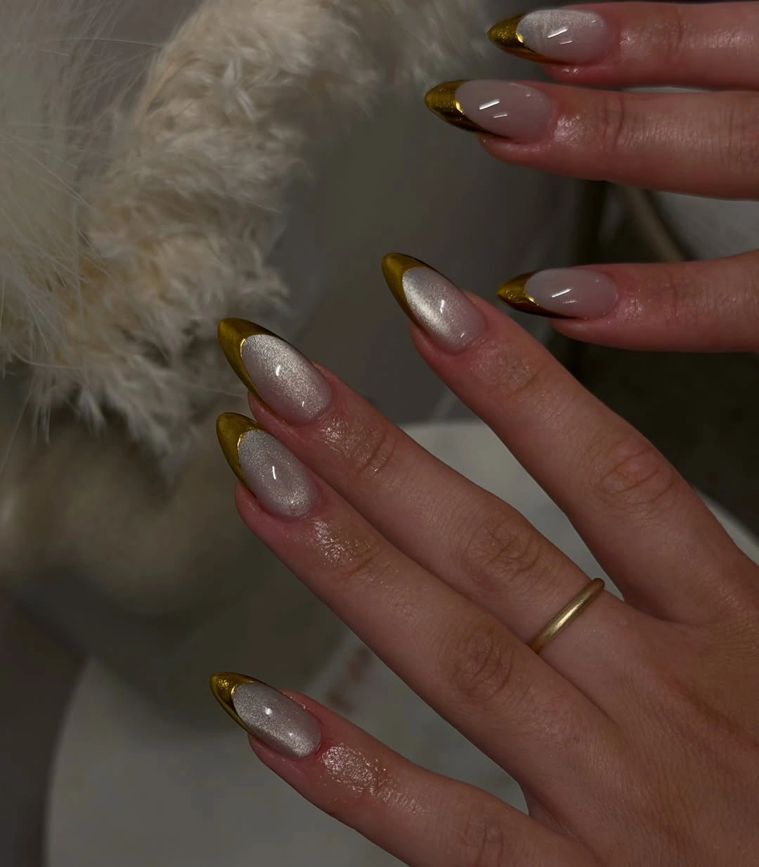 Long almond nails with nude base, pearly sheen and gold tips