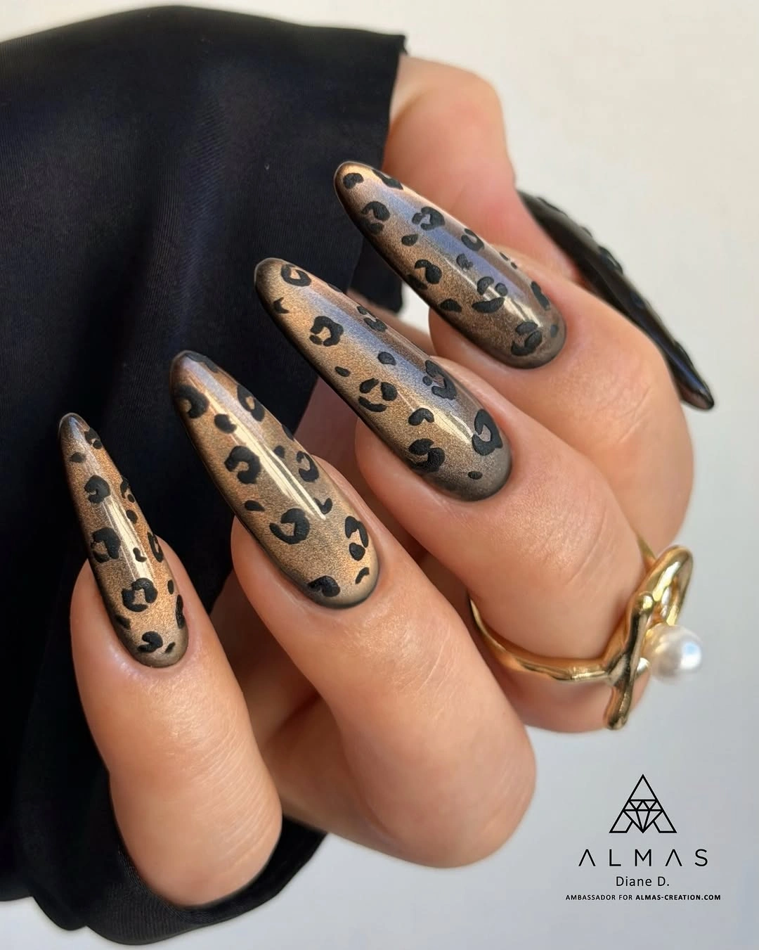 Long almond nails with metallic-looking bronze base and black leopard-like spots