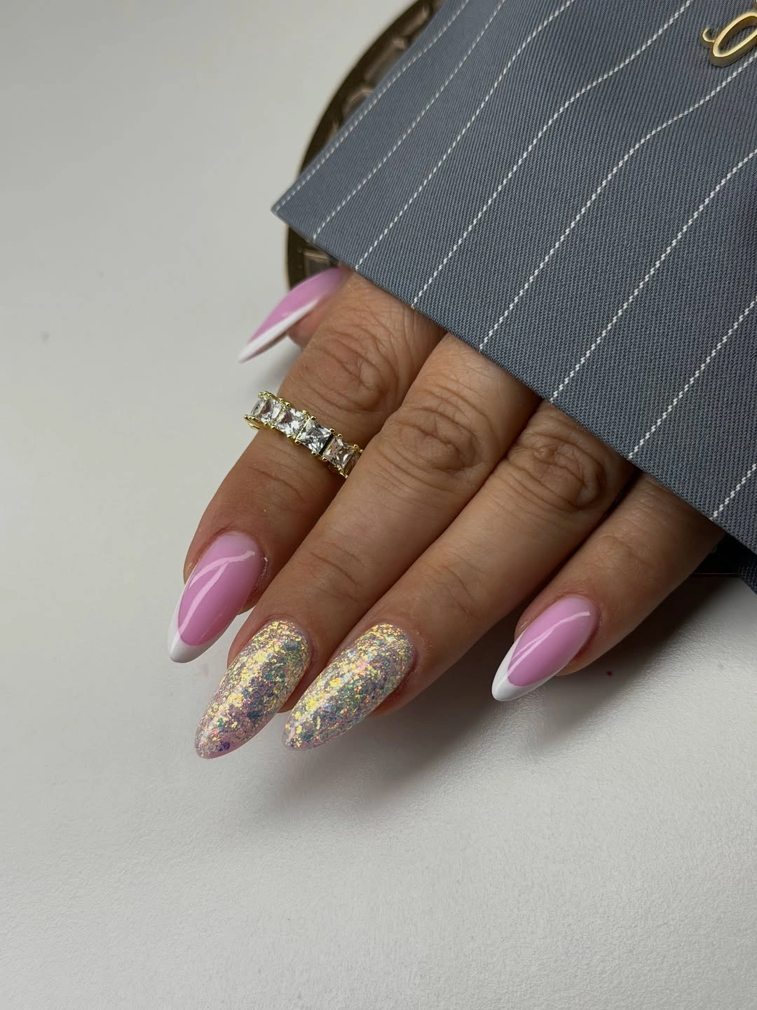Long almond nails with blush base, angled white tips and glitter-like accents