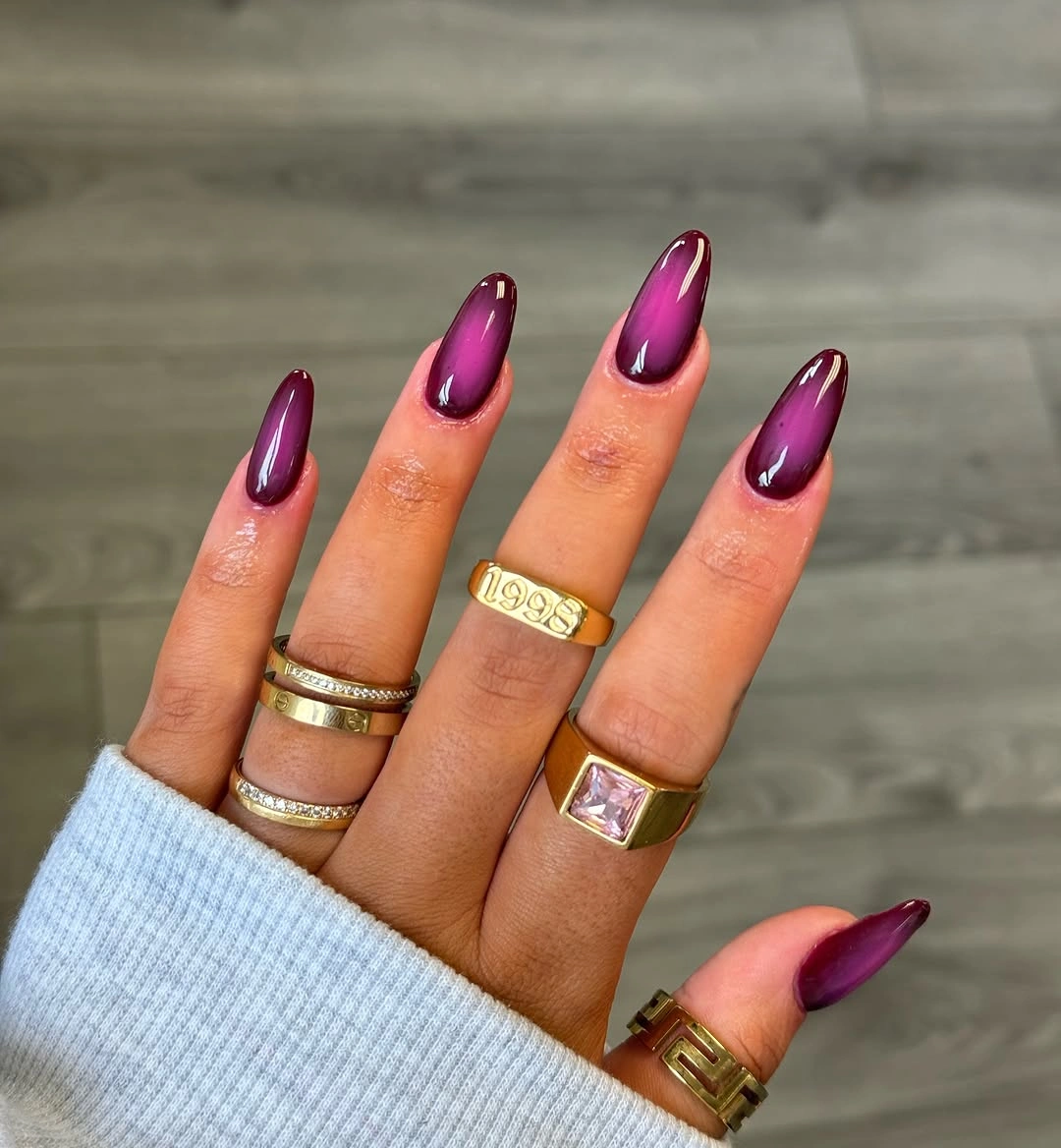 Long almond nails with glossy reflective plum-magenta finish