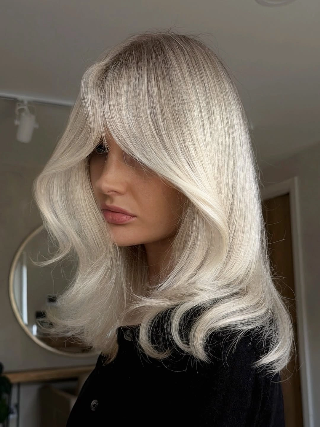 Shoulder-length silvery blonde hair with curved face-framing layers