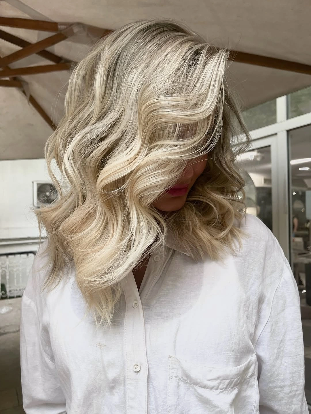 Shoulder-length beige blonde waves with deeper brown roots