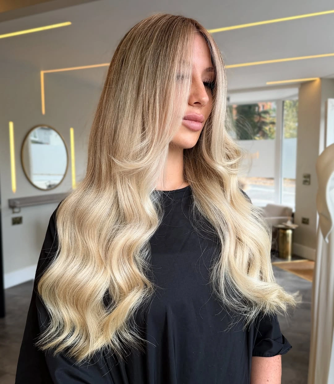 Long blonde waves with deeper beige-brown roots and pale ends