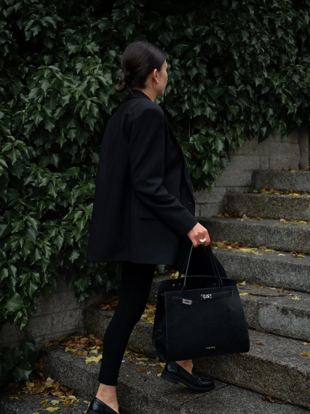 Oversized black layer over slim black pants and flat shoes