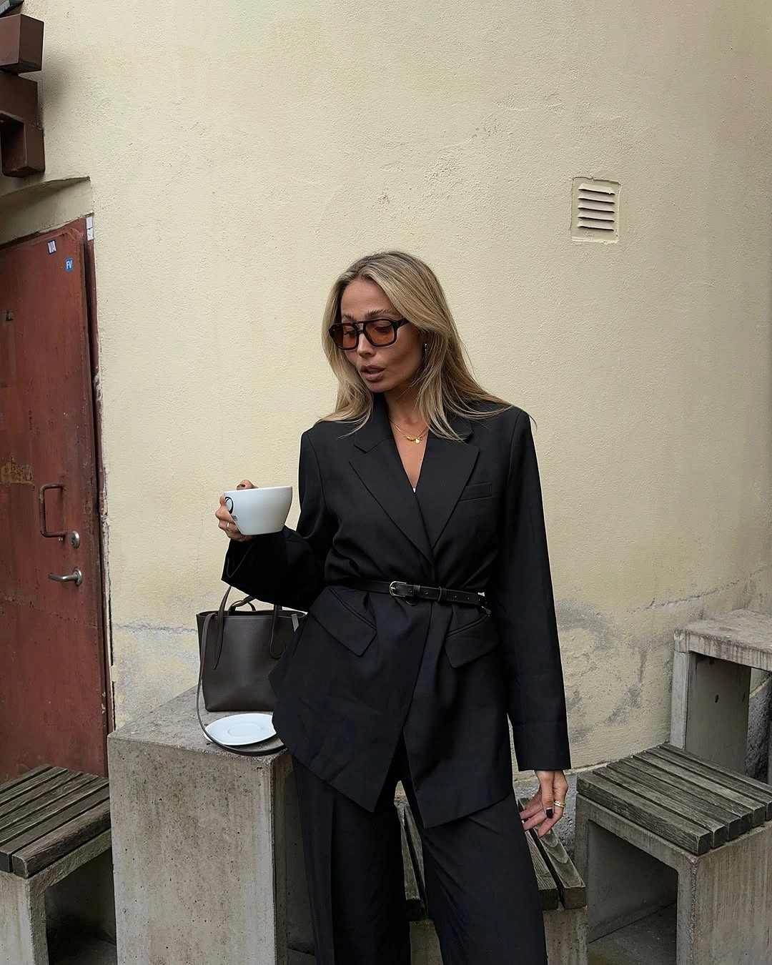 Black lapel jacket cinched over black wide trousers