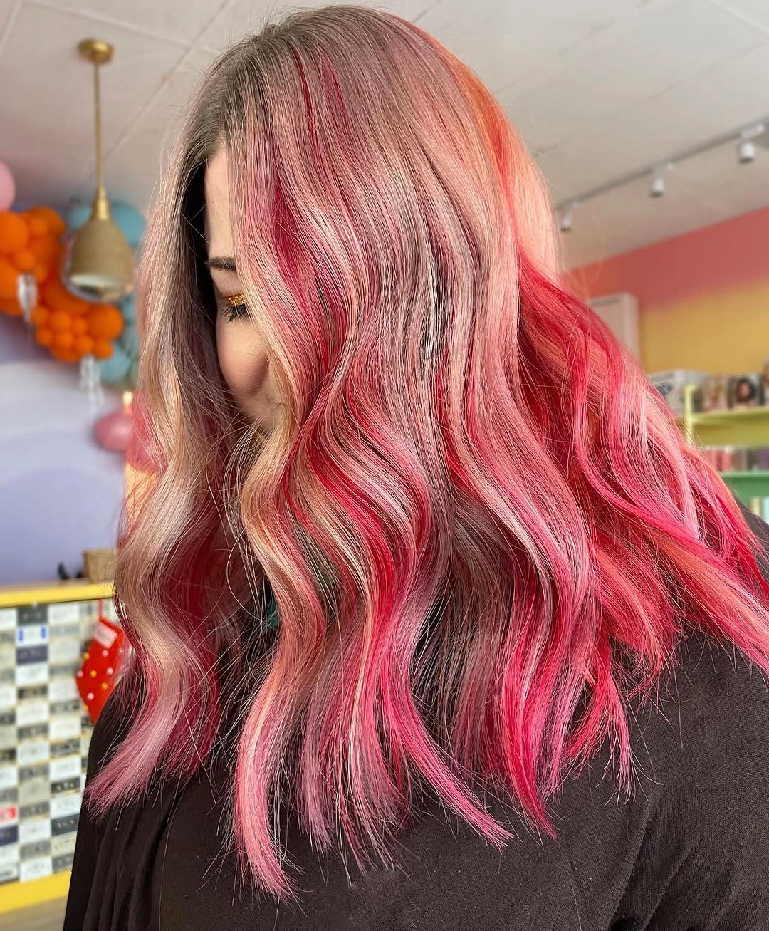 Medium brown-blonde hair with vivid pink-red sections and loose waves