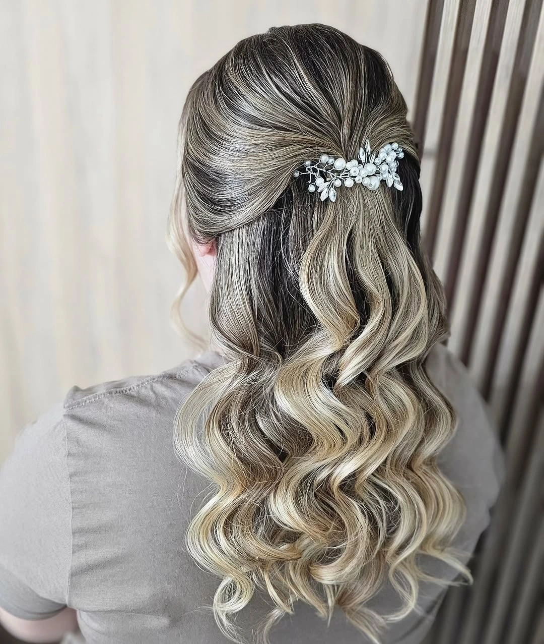 Ash-blonde half-up hair with floral accessory and defined lower waves