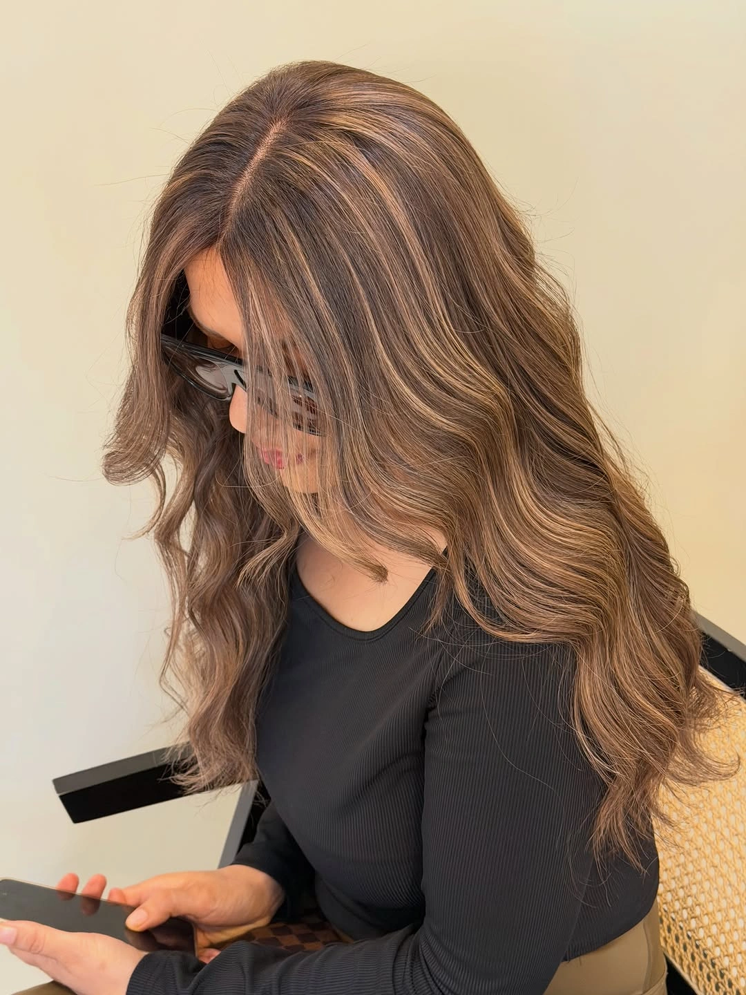 Long brown hair with lighter streaks, front layers, and loose waves