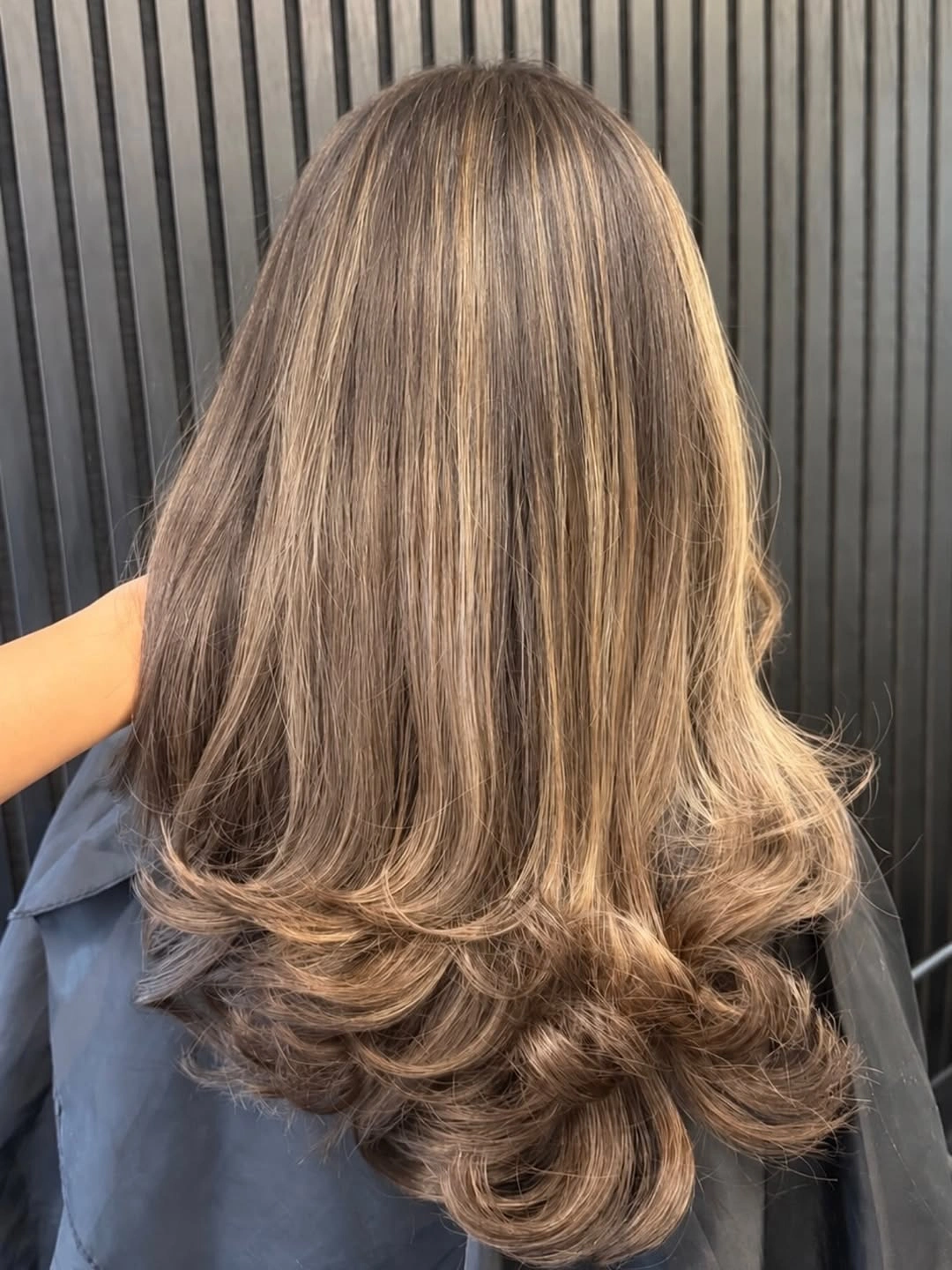 Long medium-brown hair with fine lighter streaks and rounded layered ends