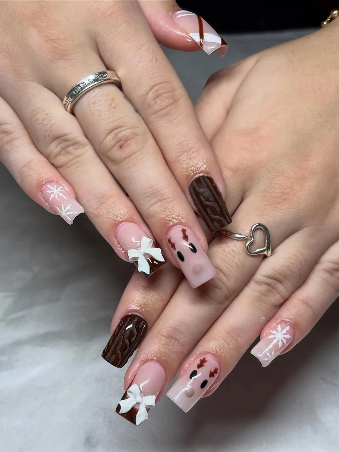 Square pink nails with snowflakes, bow, brown waves, and characters