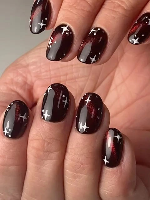 Short dark burgundy nails with white stars and red shimmer
