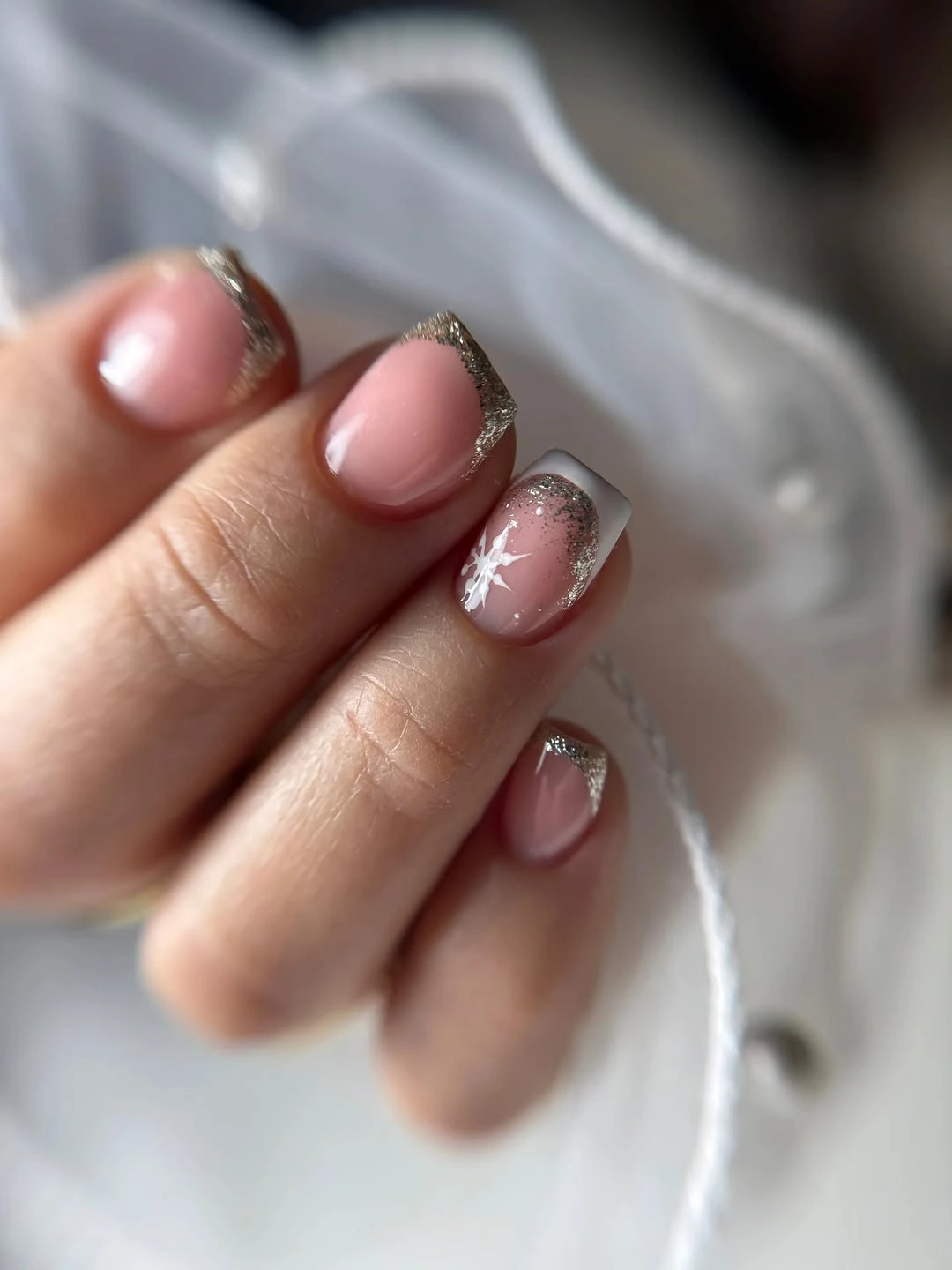 Short nude nails with silver French edges and white snowflake