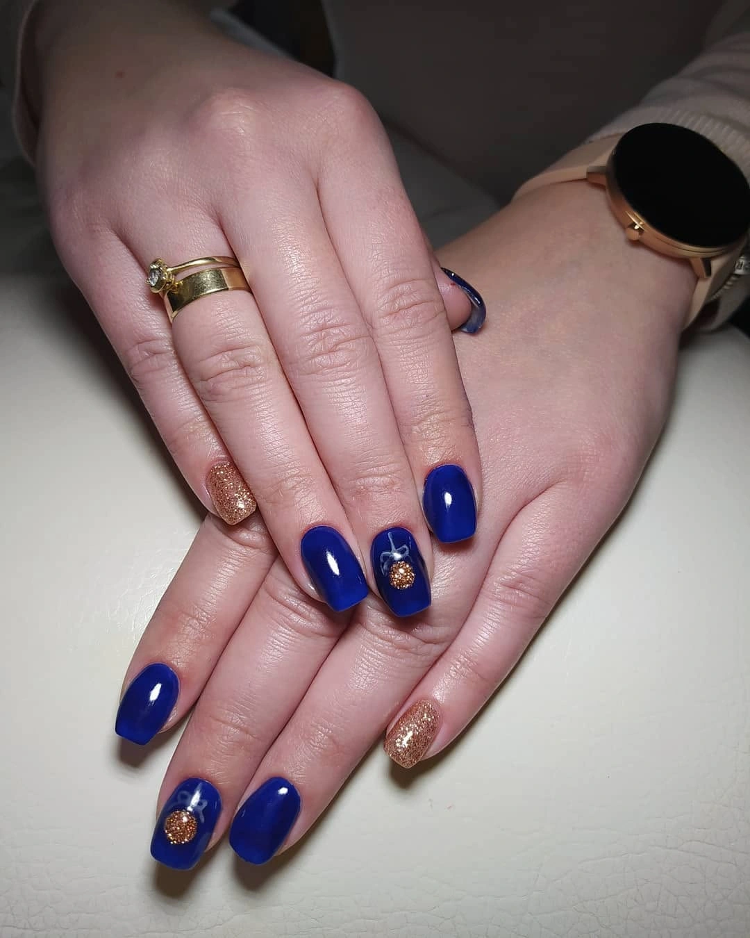 Short cobalt blue nails with gold glitter and round accent