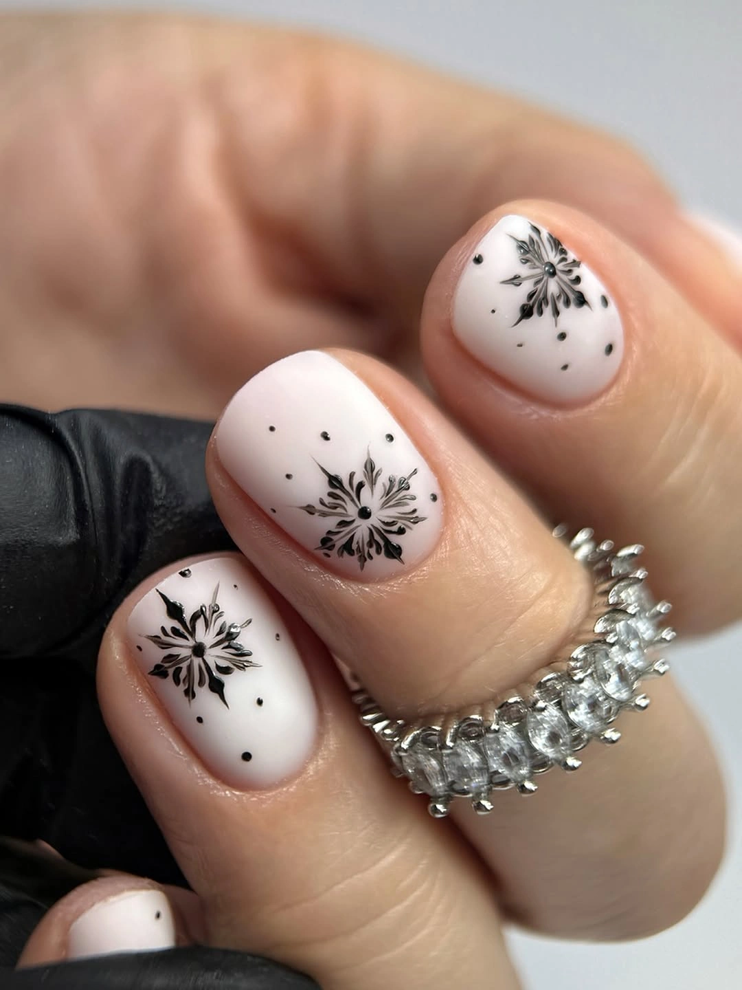 Short milky nails with black floral motifs and tiny dots