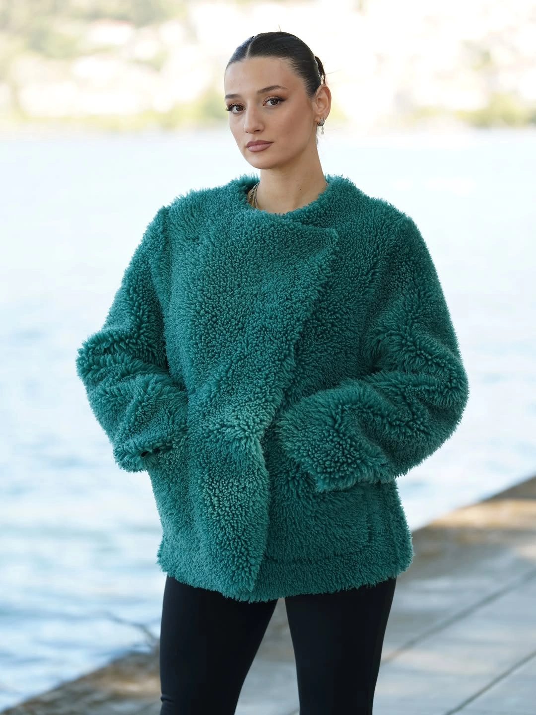 Oversized teal textured jacket with fitted black pants and minimal accessories