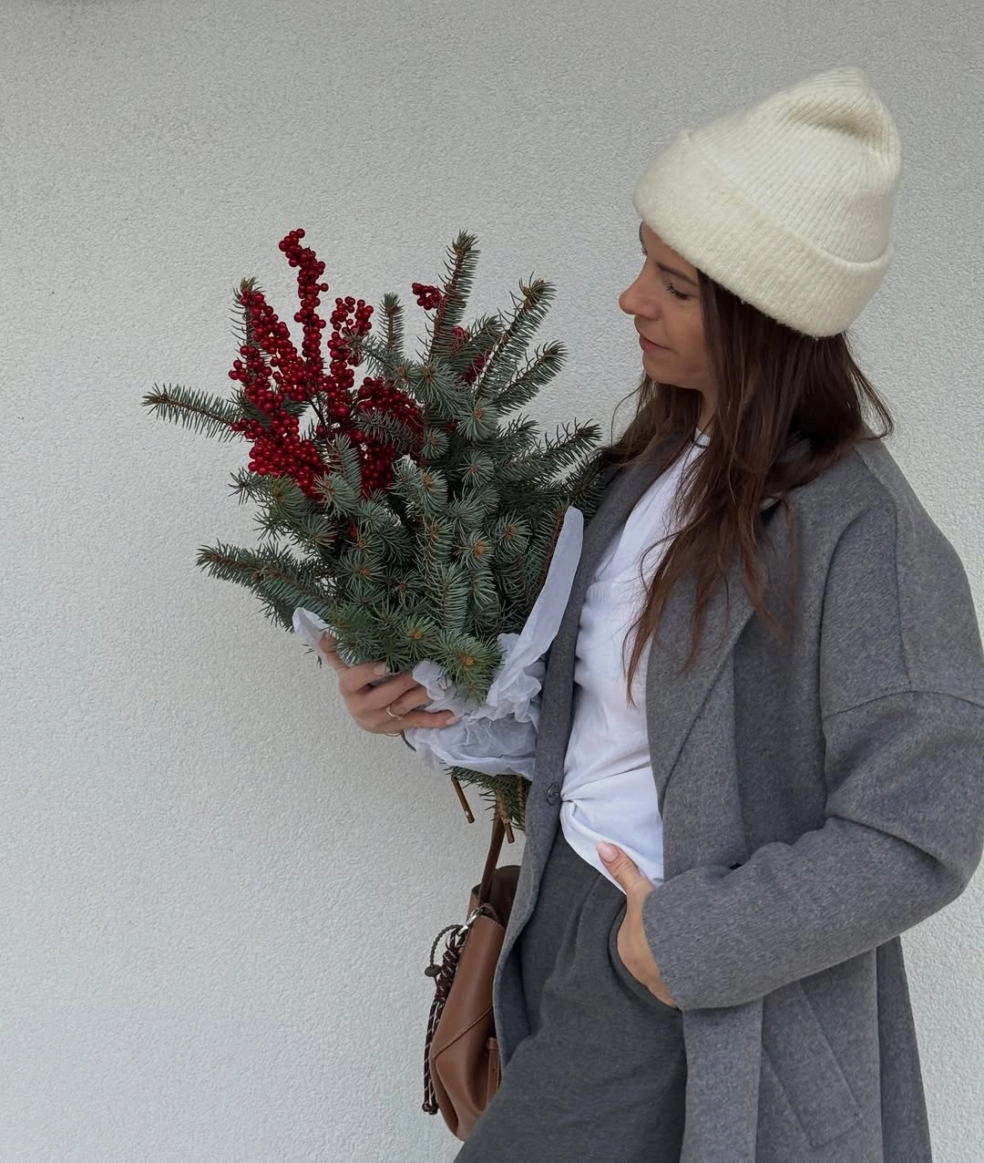 Gray jacket and trousers, white cap, brown bag, and evergreen bouquet