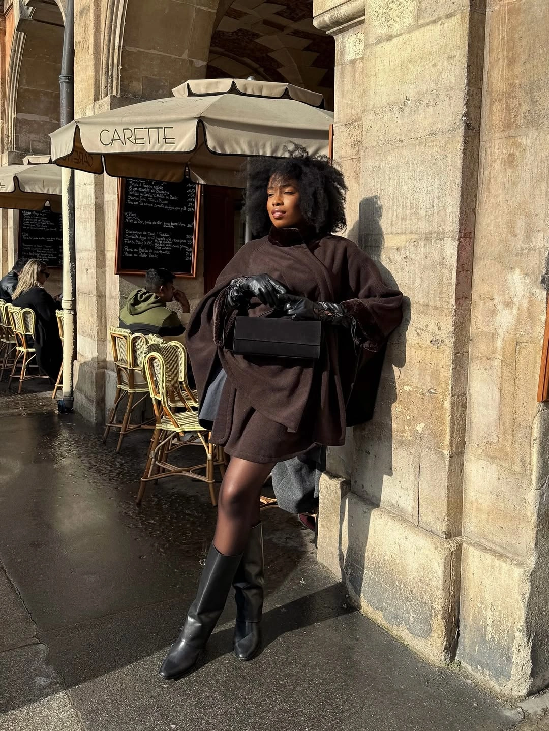 Oversized dark brown top, short hemline, black tights, boots, handbag, and gloves