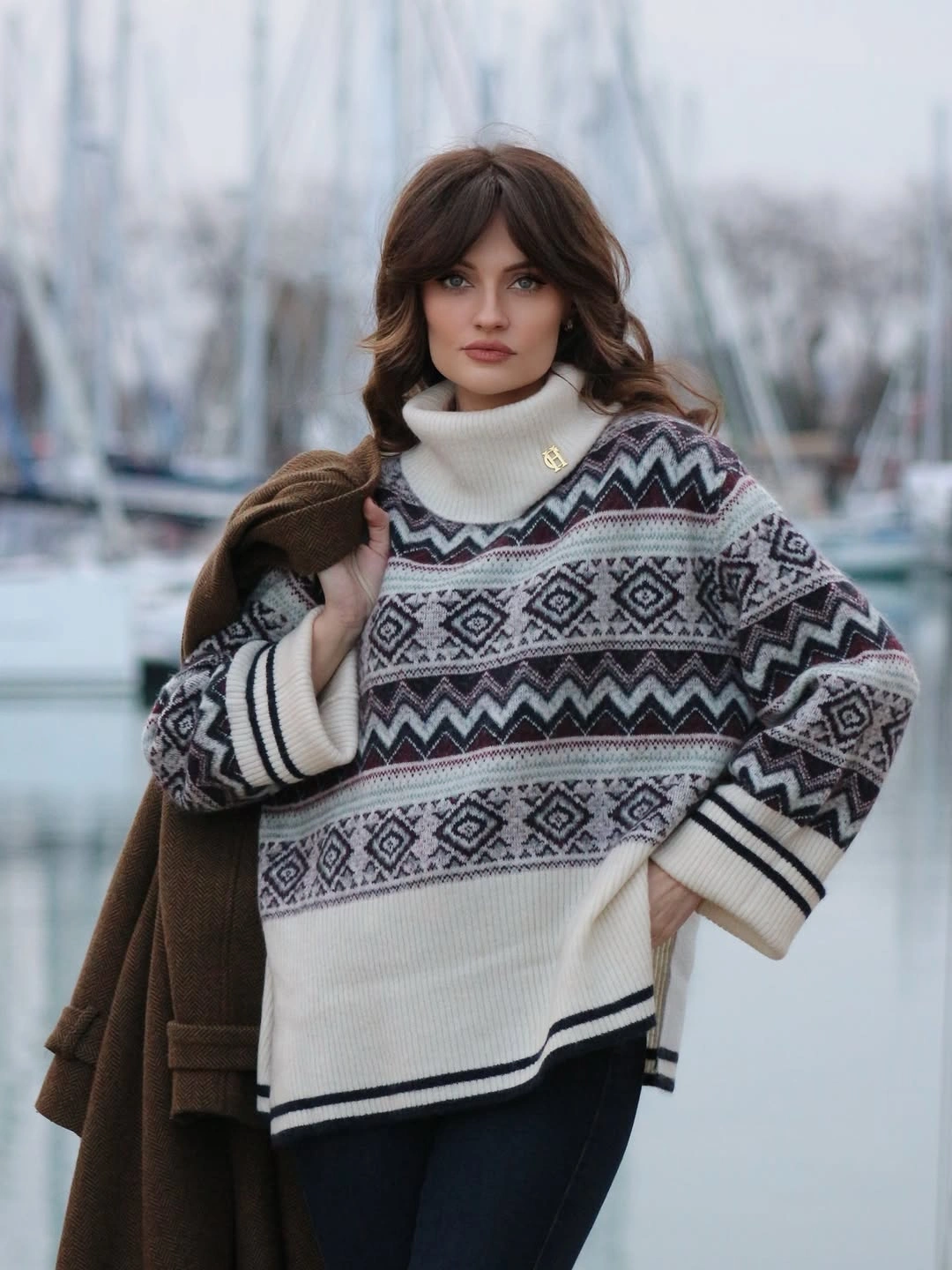 Geometric white-and-dark sweater, dark pants, white high neck, and brown coat