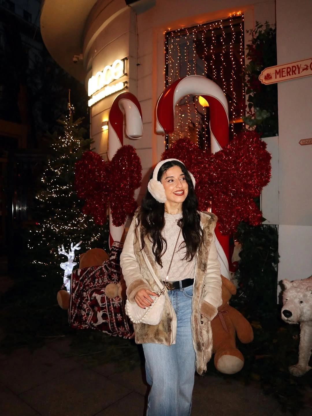Pale sleeveless layer, light top, blue jeans, earmuffs, and crossbody bag