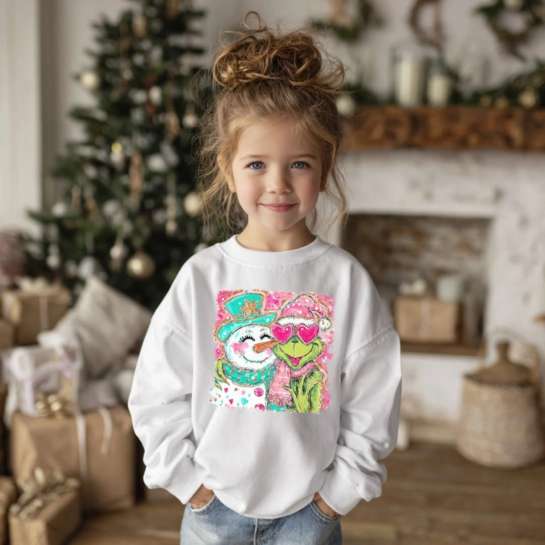 Child in white graphic sweatshirt and light jeans by Christmas tree