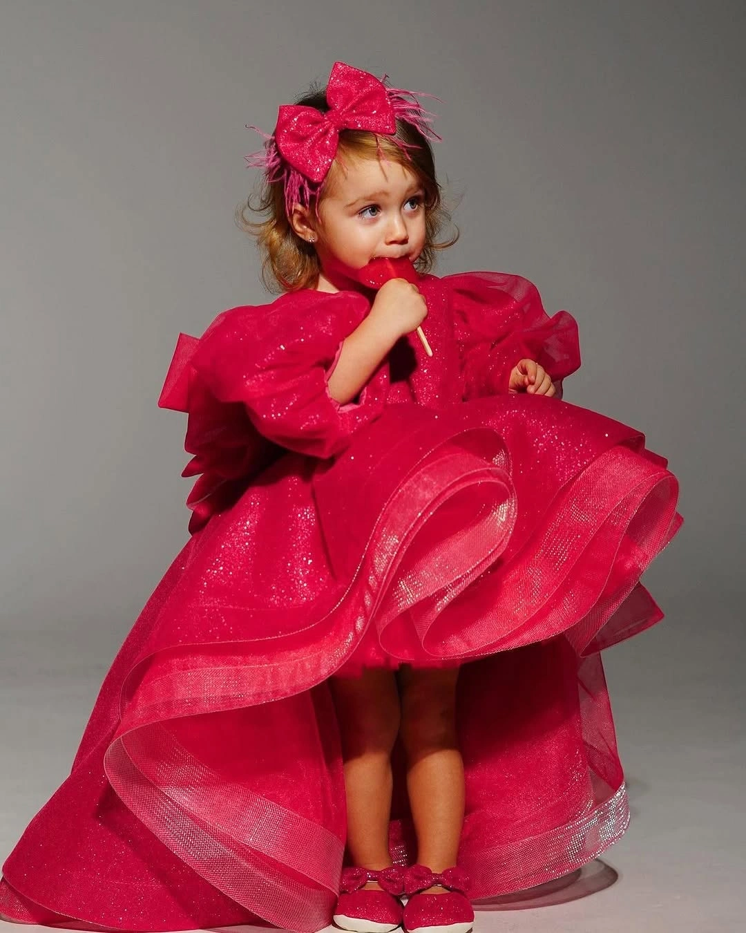 Child in bright pink layered dress with matching bow and shoes