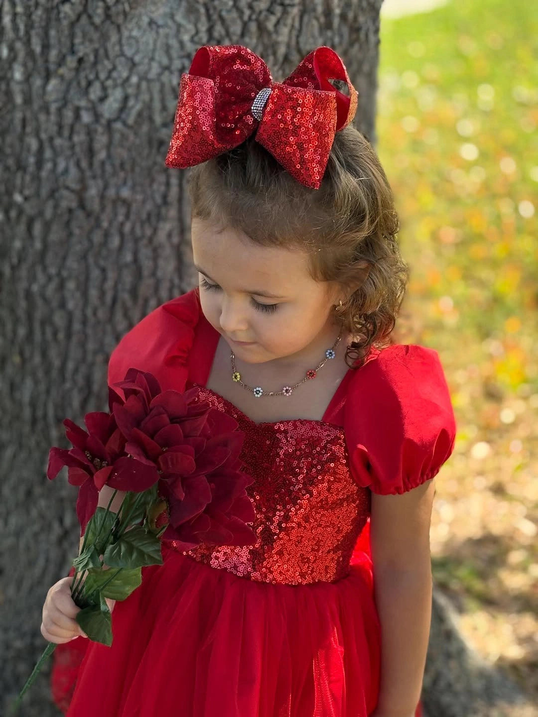 Child in red dress with large red bow and flowers
