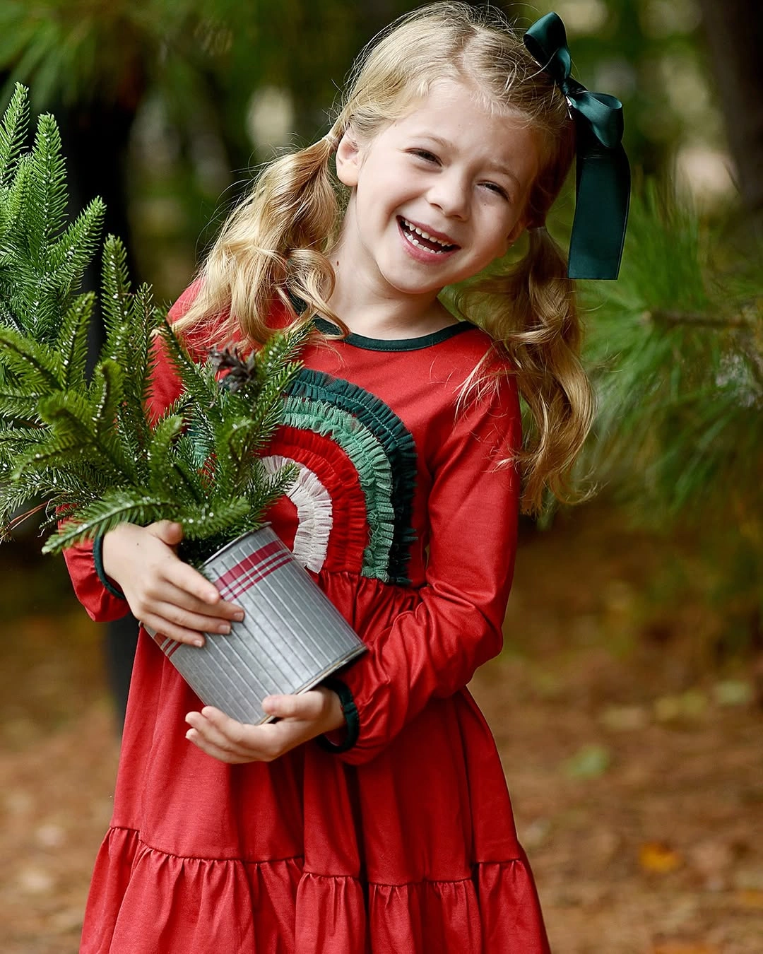Child in red dress with green trim and large hair bow