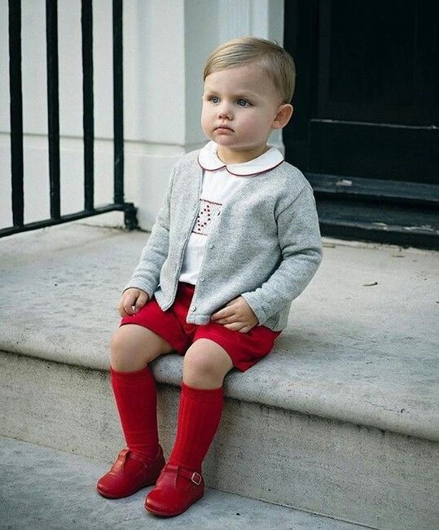 Child in gray cardigan red shorts socks and shoes