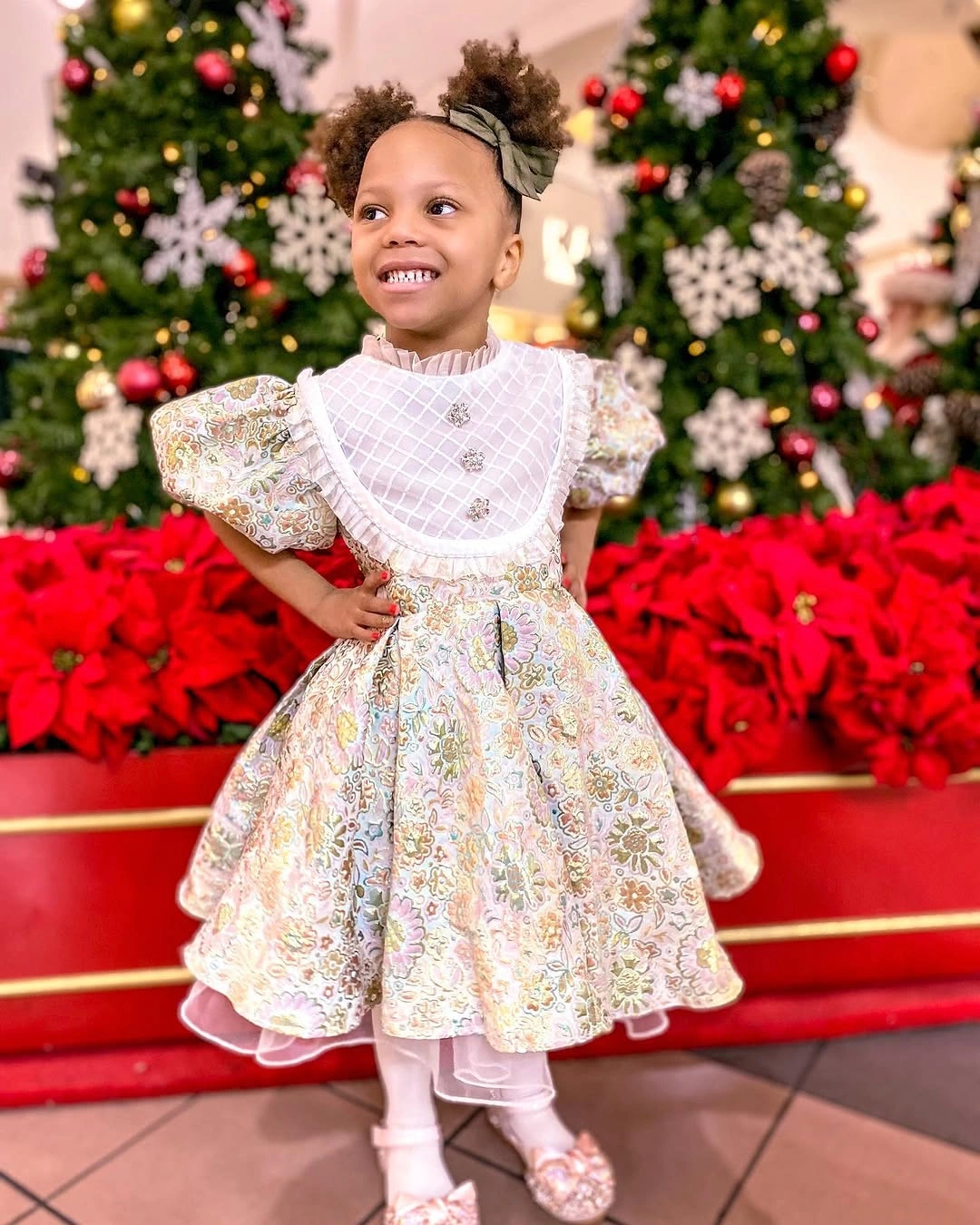 Child in cream patterned dress with white panel and tights