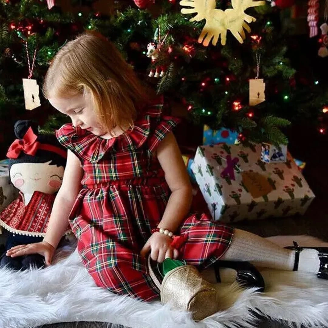Child in tartan dress with gold bag and white tights