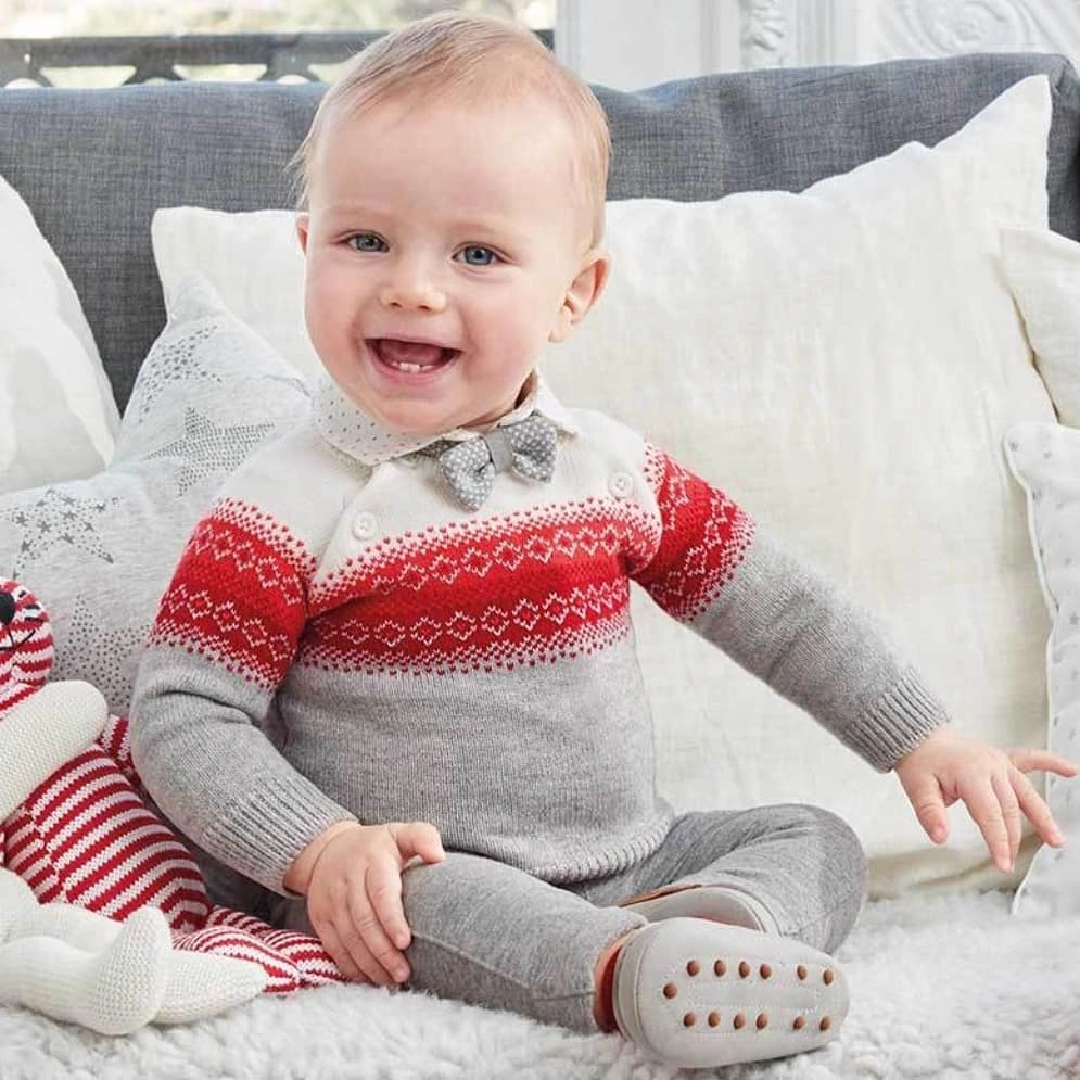 Child in gray one-piece with red patterned chest band and bow tie