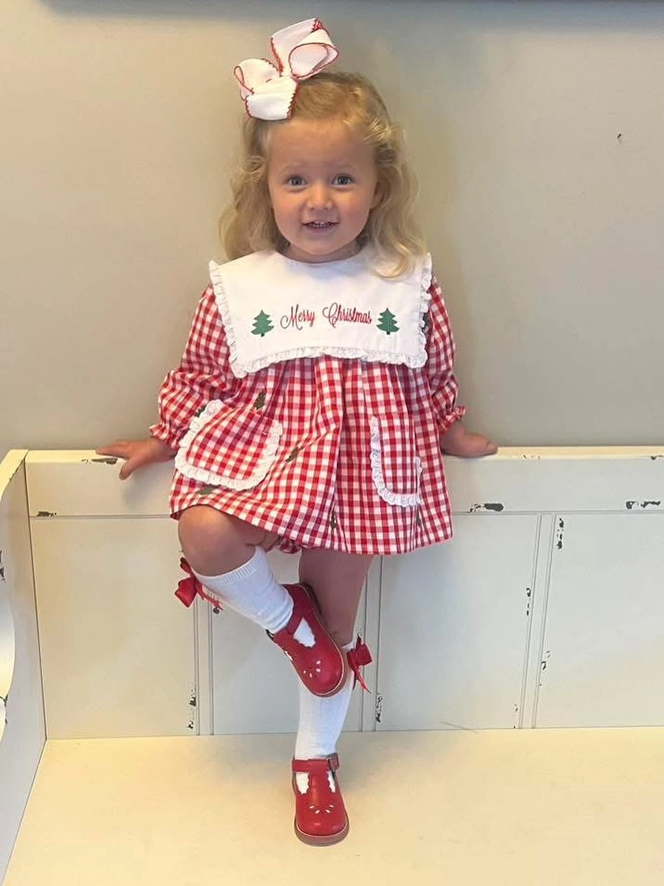 Child in red gingham dress with white bib and red bows