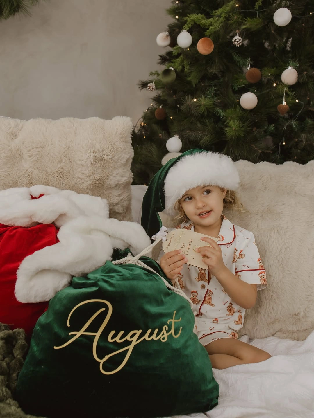 Child in pale printed short set with green Santa-style hat