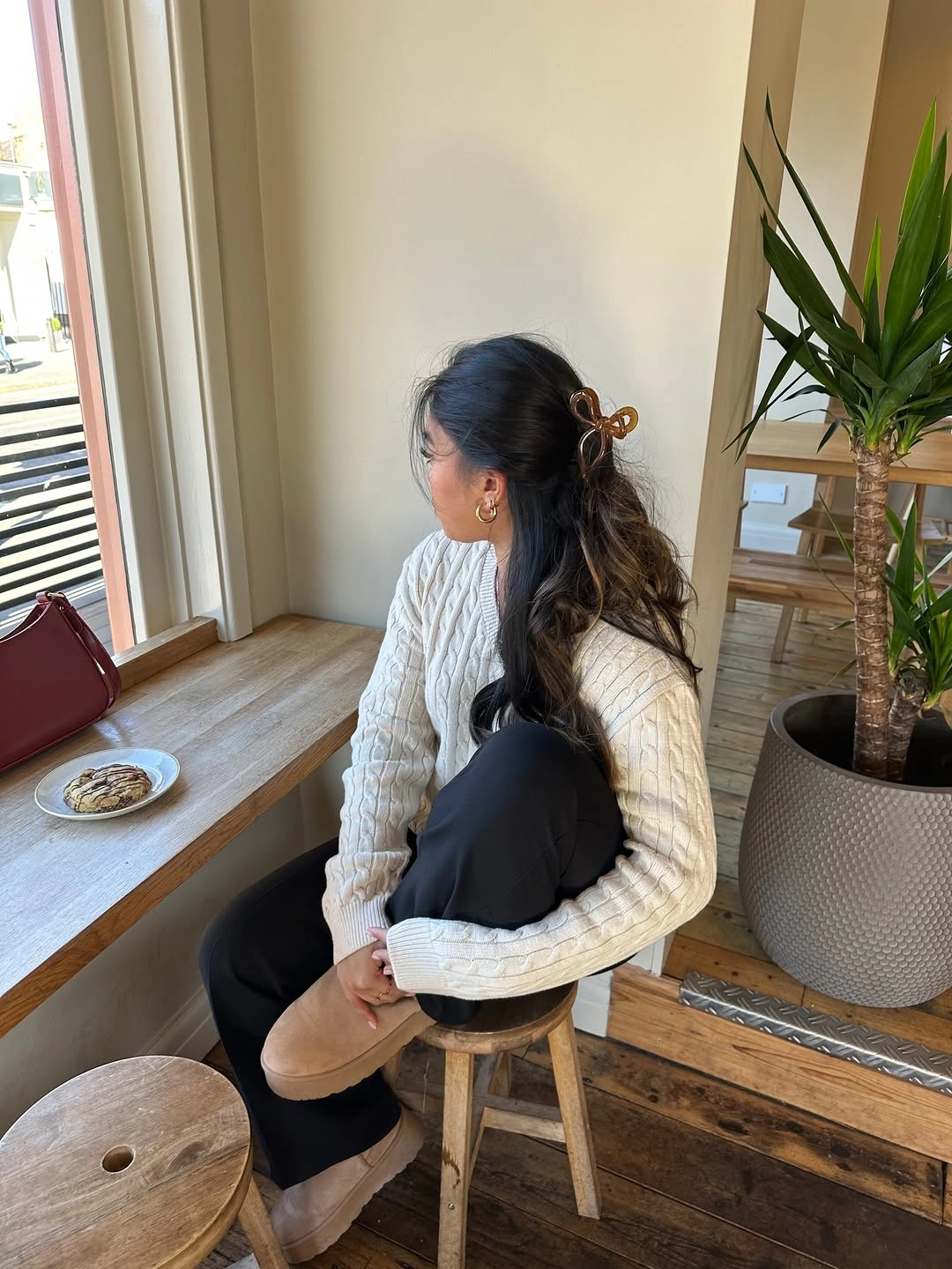 Cream textured sweater with black trousers and beige shearling slippers