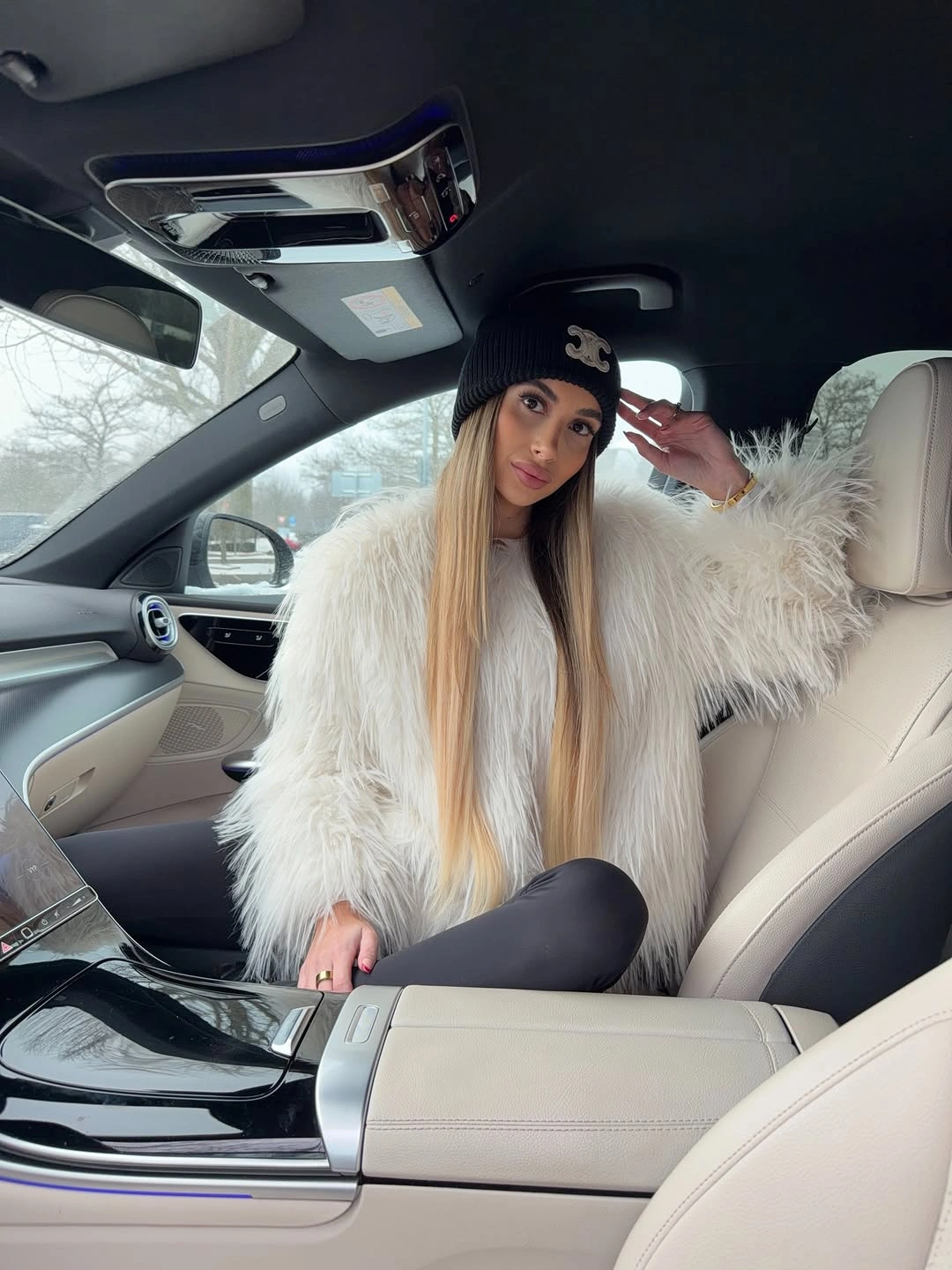 Oversized cream fuzzy coat with black leggings and dark knit cap