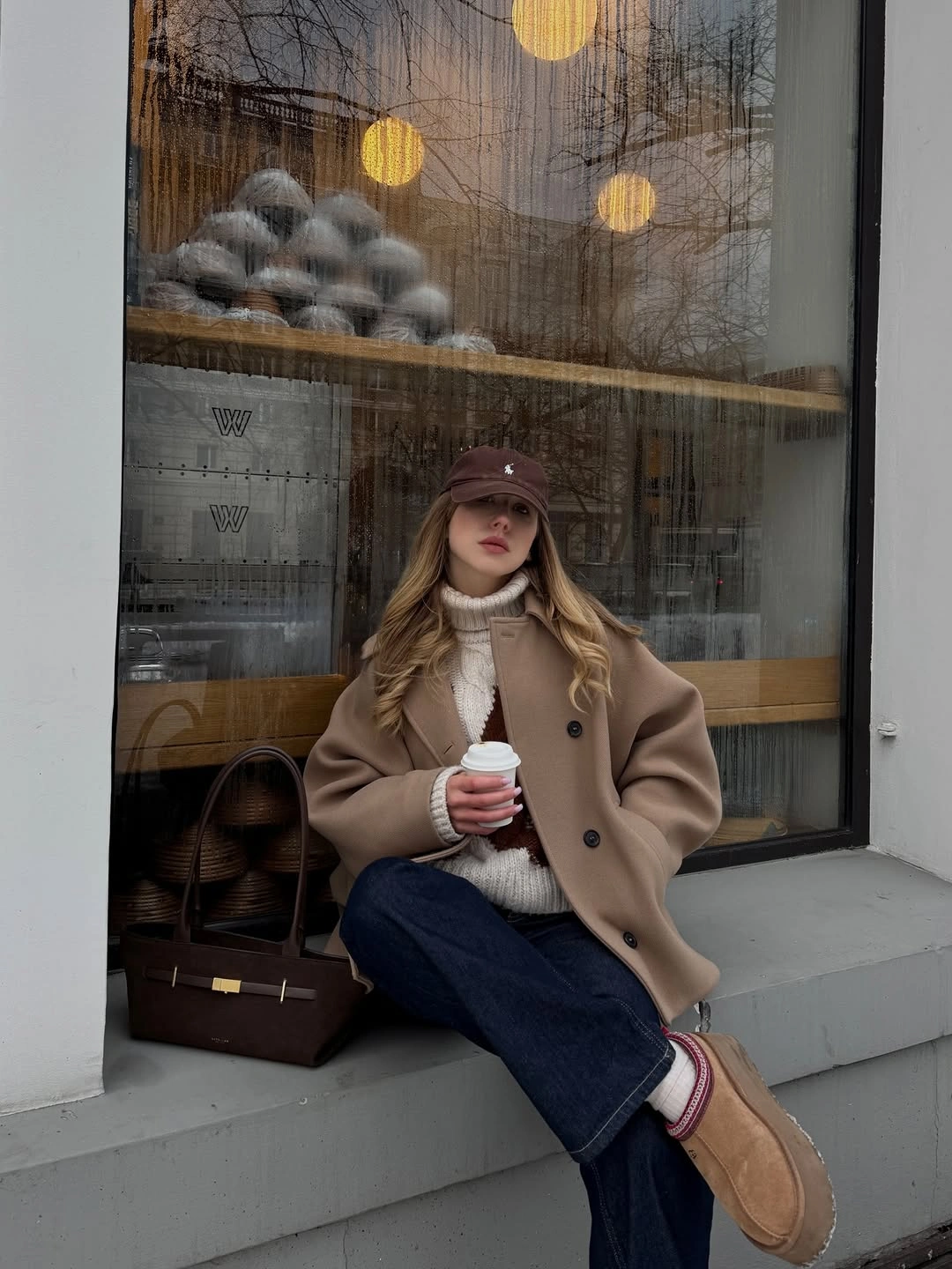 Camel double-breasted coat with cream ribbed knit, dark jeans, and brown shoes