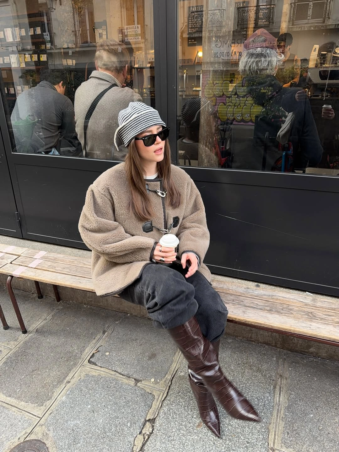 Oatmeal fleece jacket with gray relaxed pants, striped beanie, and tall brown boots